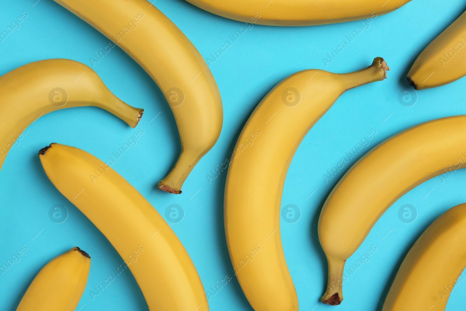 Photo of Ripe yellow bananas on turquoise background, flat lay