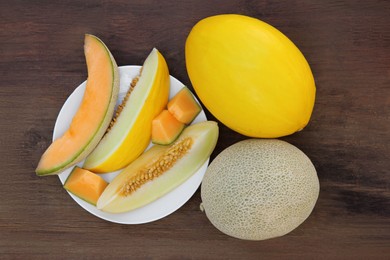Whole and cut ripe melons on wooden table, flat lay
