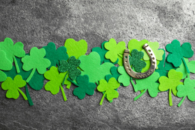 Photo of Flat lay composition with clover leaves and horseshoe on grey stone background. St. Patrick's day