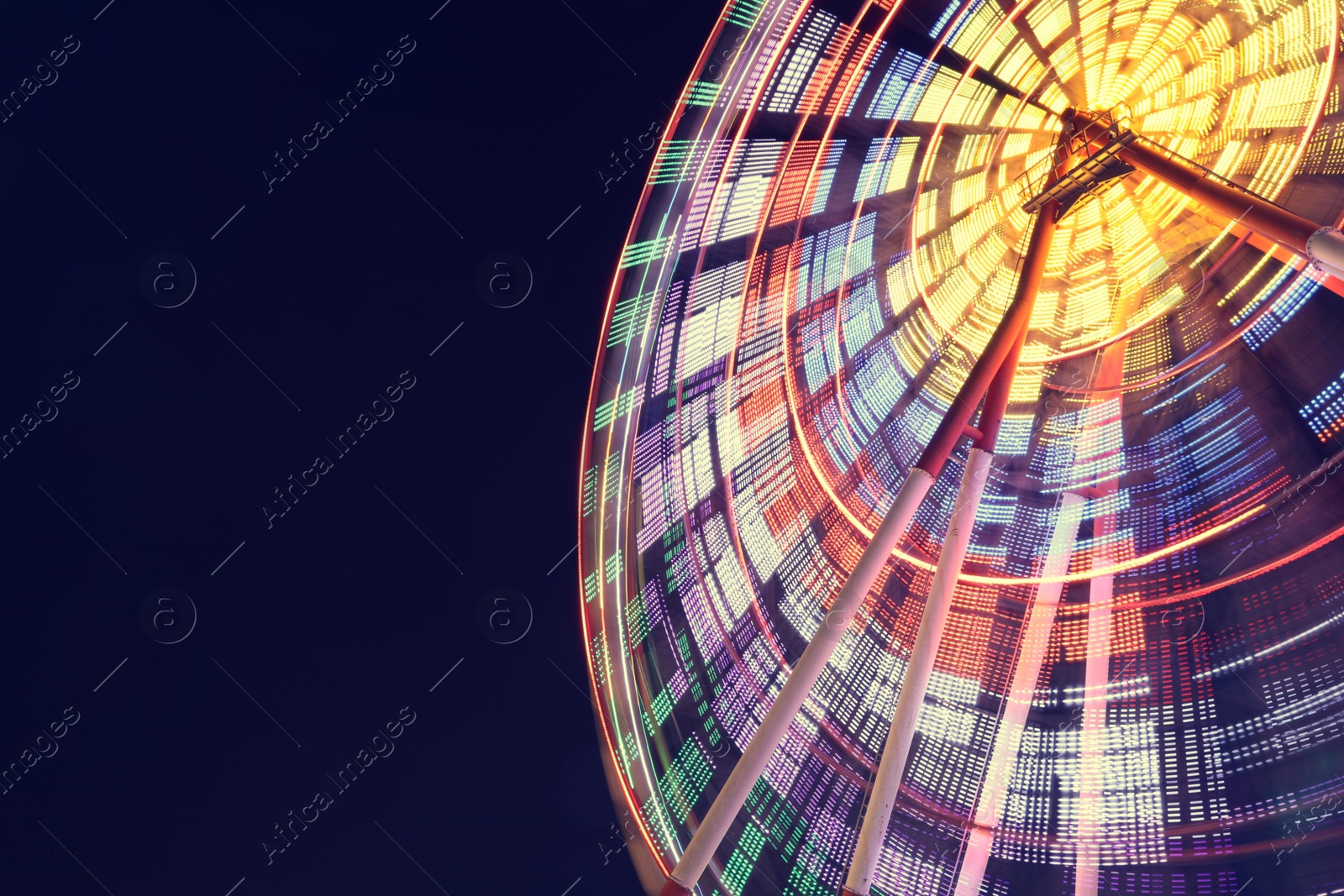 Photo of Beautiful glowing Ferris wheel against dark sky, low angle view. Space for text