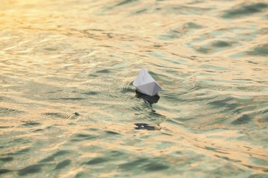 Paper boat floating on water outdoors. Space for text