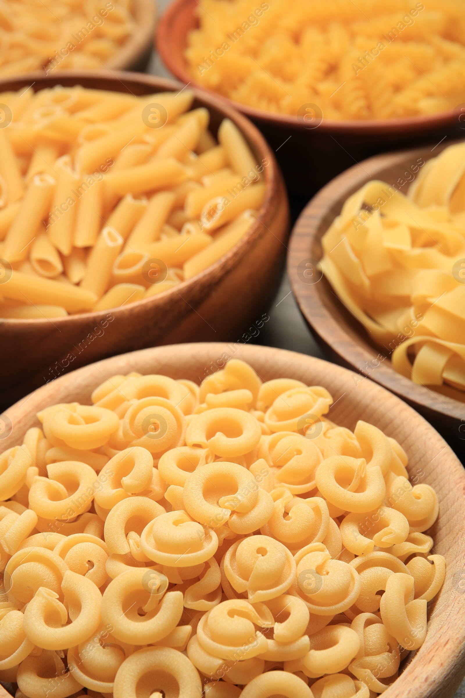 Photo of Different types of pasta in bowls on table, closeup