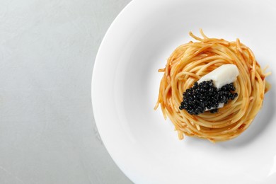 Photo of Tasty spaghetti with tomato sauce and black caviar on light grey table, top view. Exquisite presentation of pasta dish