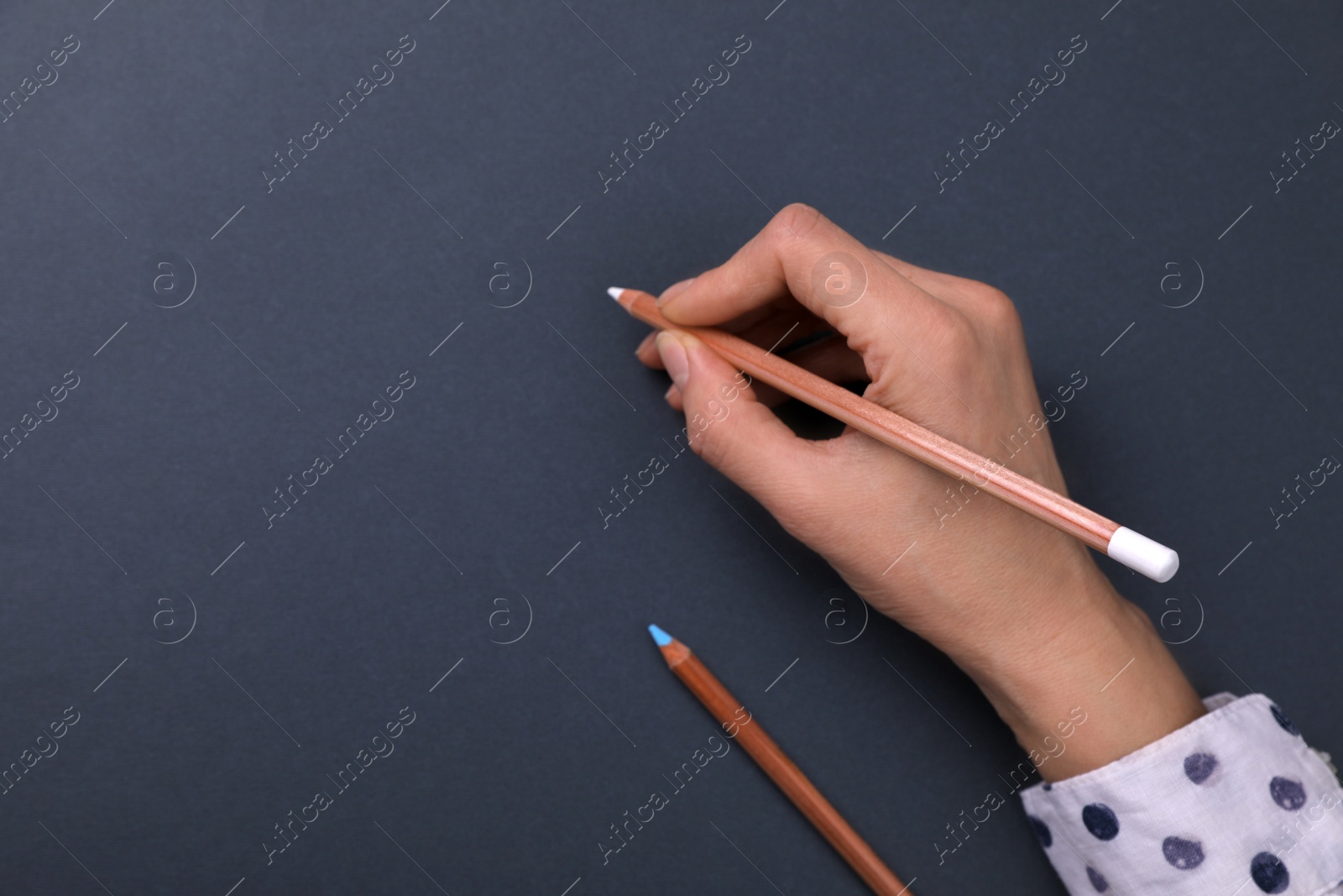 Photo of Woman drawing on black paper with pastel pencil, top view. Space for text