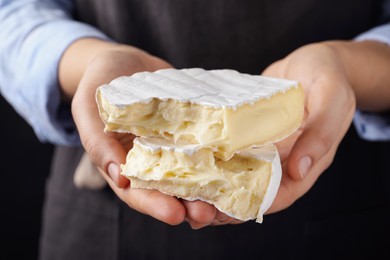 Photo of Woman with pieces of delicious brie cheese on black background, closeup