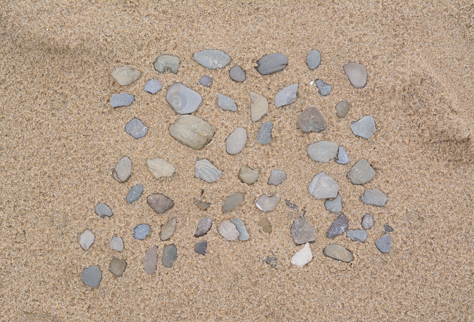 Photo of Many stones on wet sand, top view