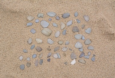 Photo of Many stones on wet sand, top view