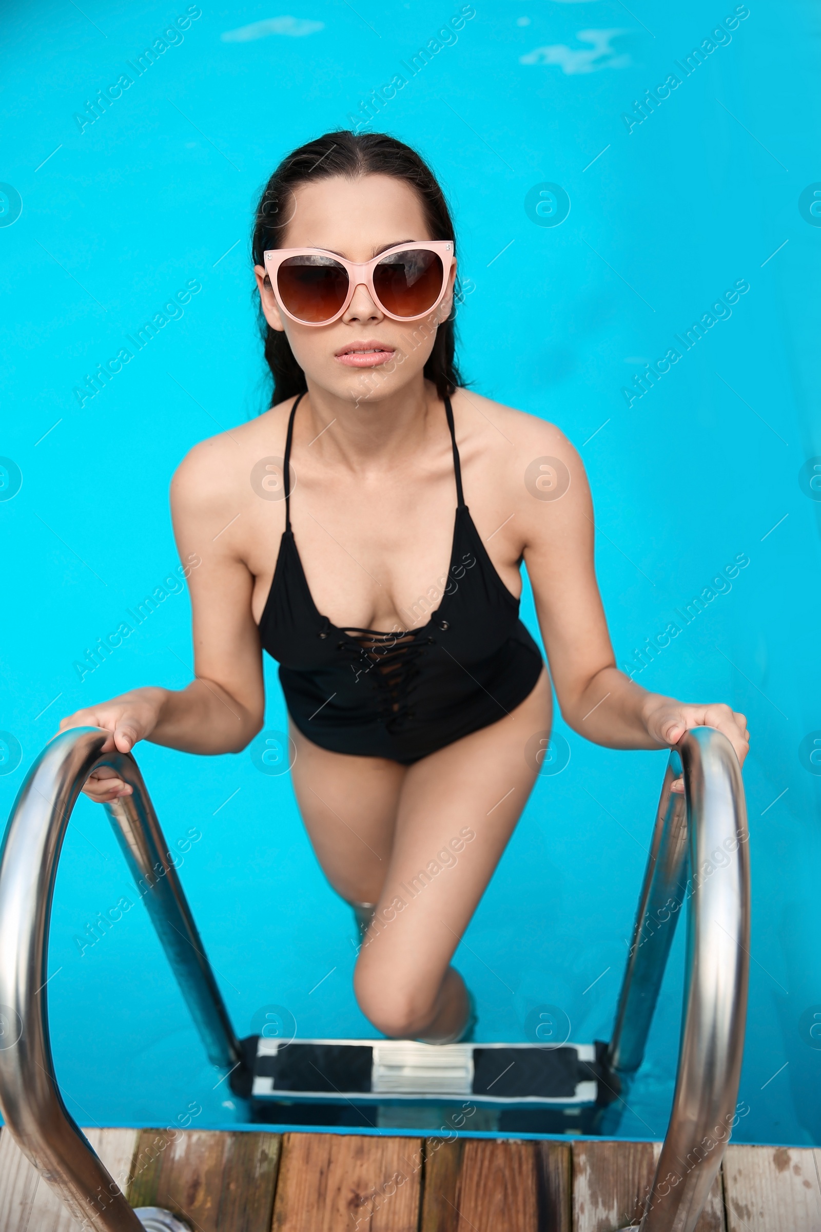 Photo of Beautiful young woman getting out of blue swimming pool