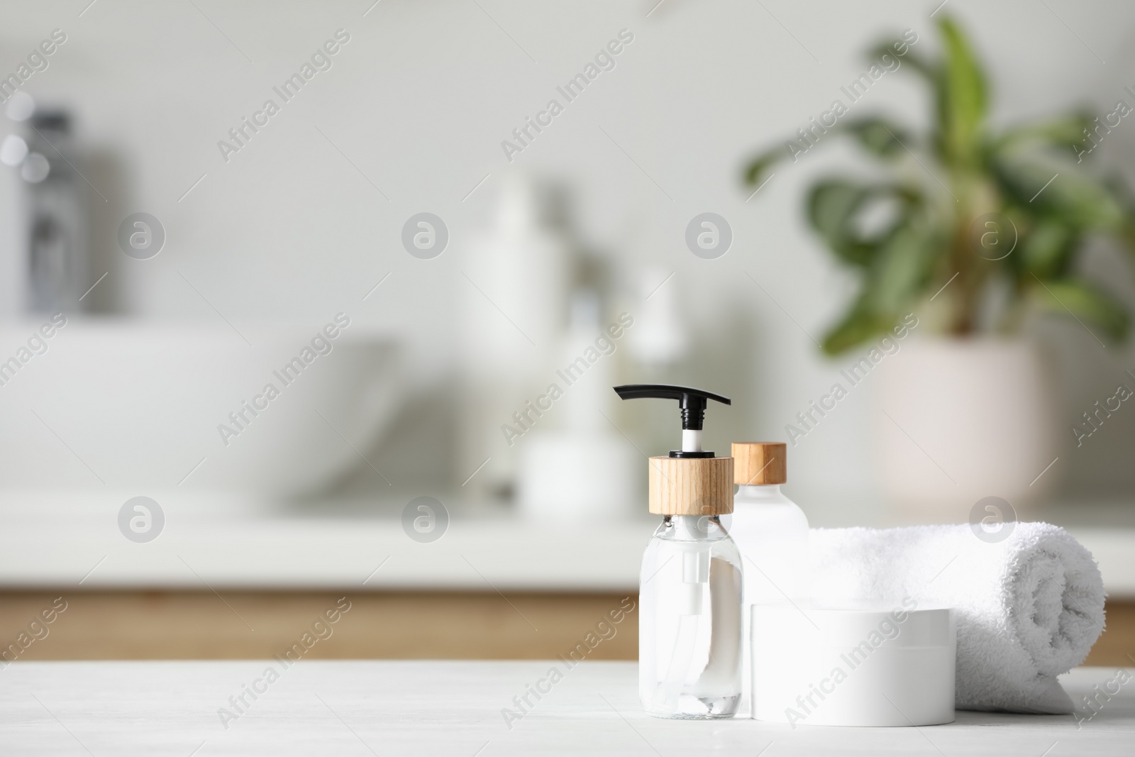 Photo of Different personal care products and rolled towel on white wooden table in bathroom. Space for text