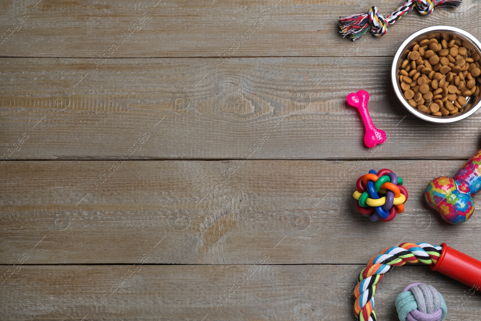 Photo of Flat lay composition with different pet toys and feeding bowl on wooden background, space for text
