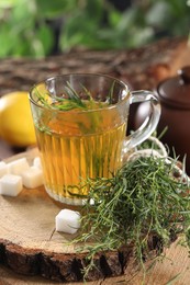 Aromatic herbal tea, fresh tarragon sprigs and sugar cubes on table, closeup