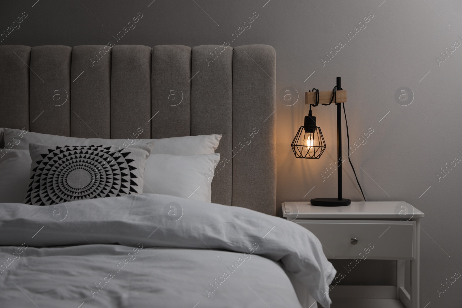 Photo of Stylish lamp on bedside table indoors. Bedroom interior elements