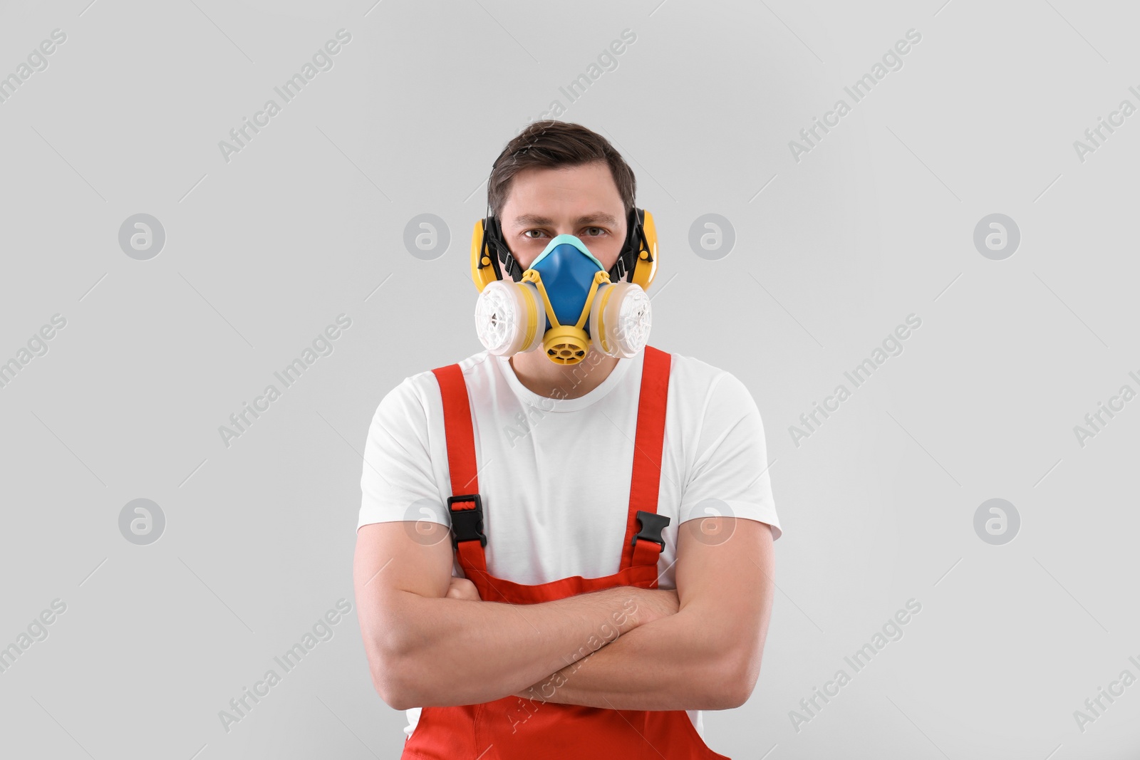 Photo of Male industrial worker in uniform on light background. Safety equipment