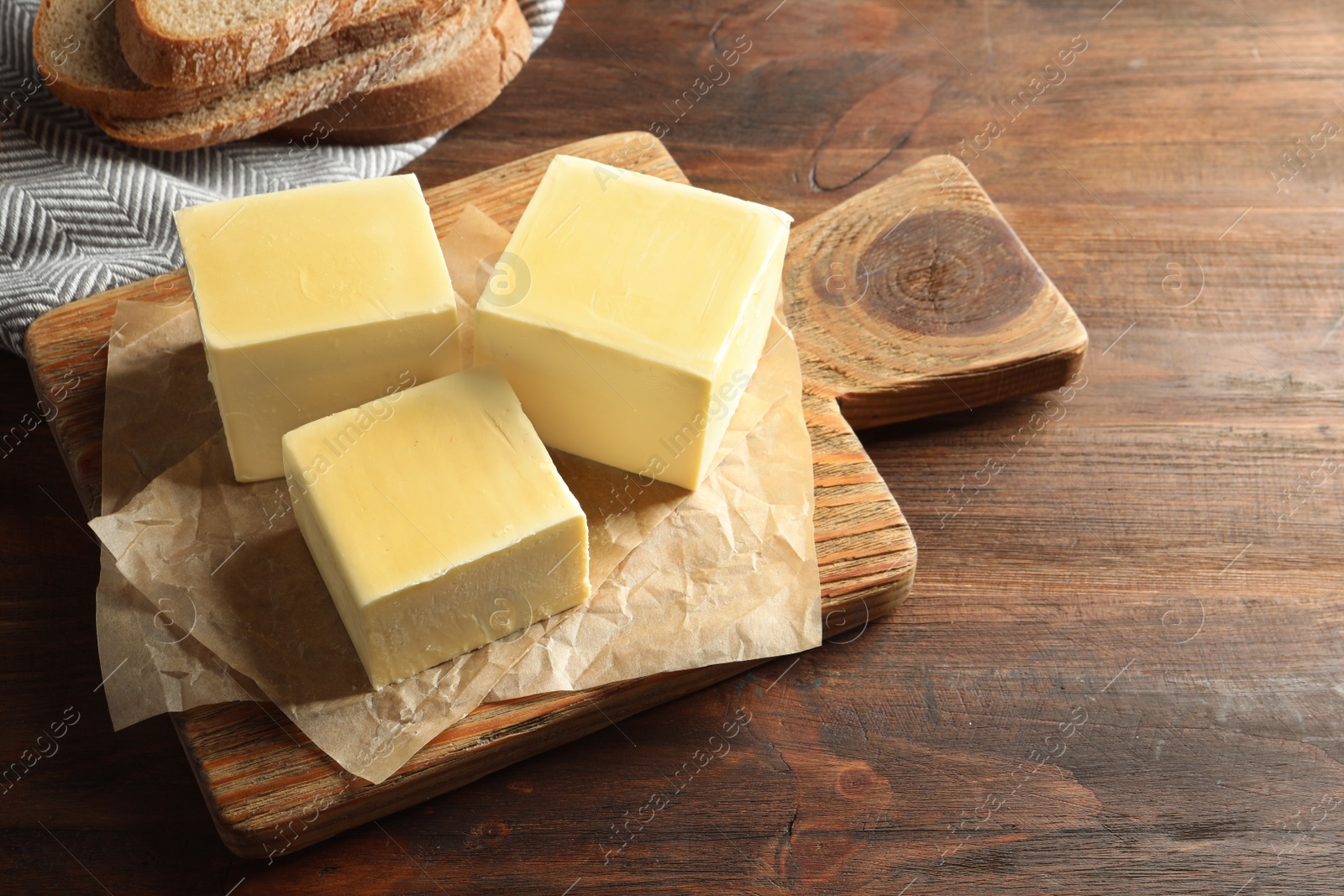 Photo of Wooden board with fresh butter on table. Space for text