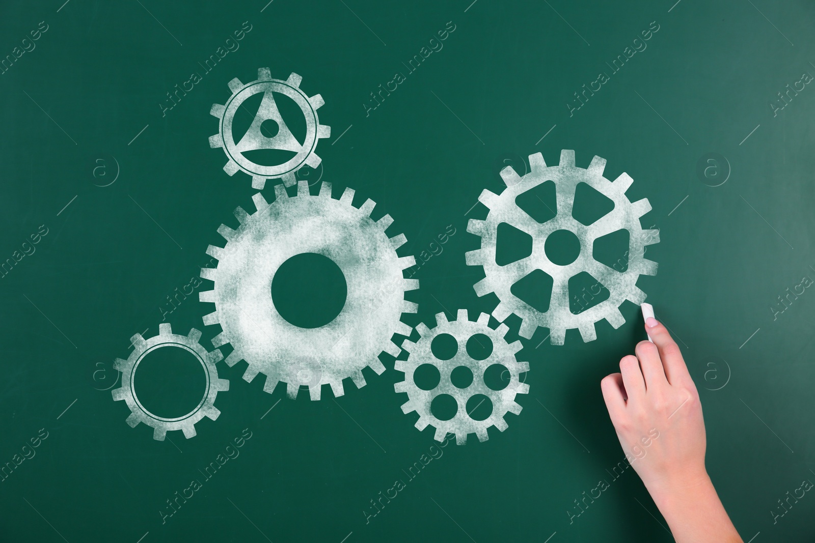 Image of Woman drawing gear mechanism on chalkboard, closeup 