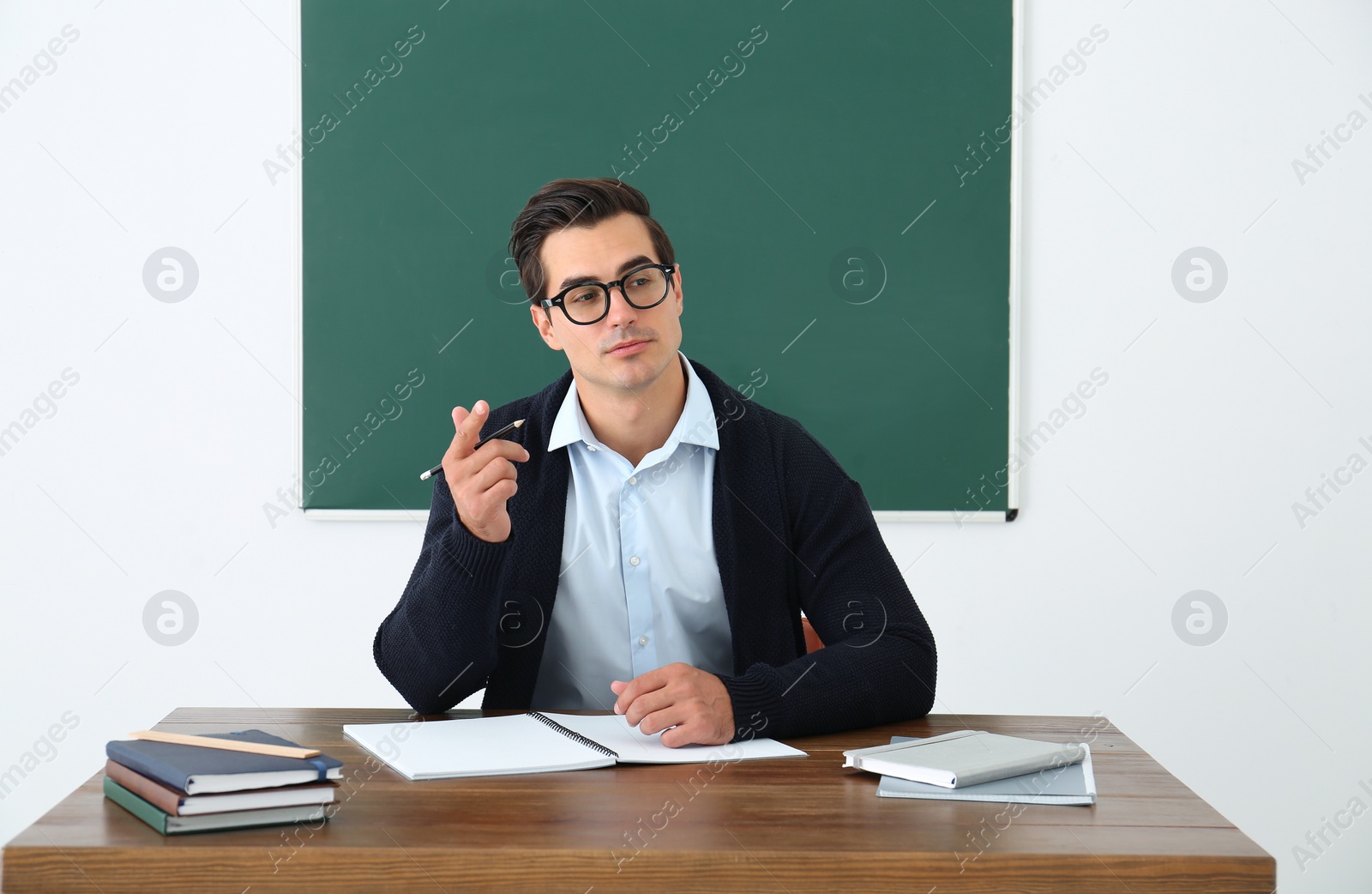 Photo of Young teacher working at table in classroom