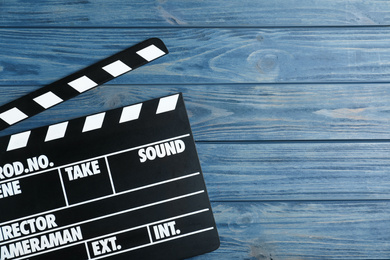 Photo of Clapper board on blue wooden background, top view with space for text. Cinema production