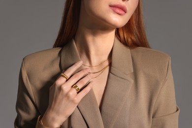 Beautiful woman with elegant jewelry on gray background, closeup