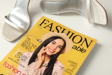 Fashion magazine, shoes and jewelry on white table