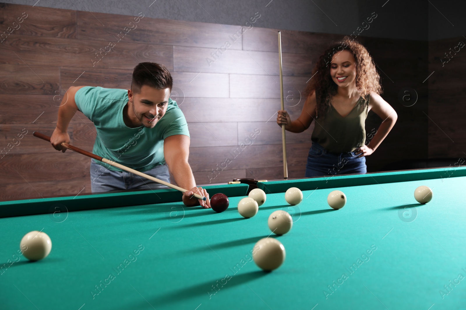 Photo of Young man and woman playing billiard indoors