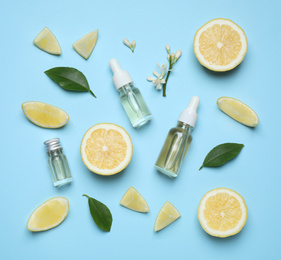 Flat lay composition with bottles of citrus essential oil on light blue background