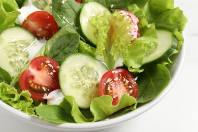 Delicious salad in bowl on white table, closeup