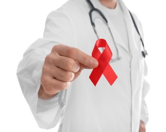 Doctor holding red awareness ribbon on white background, closeup. World AIDS disease day