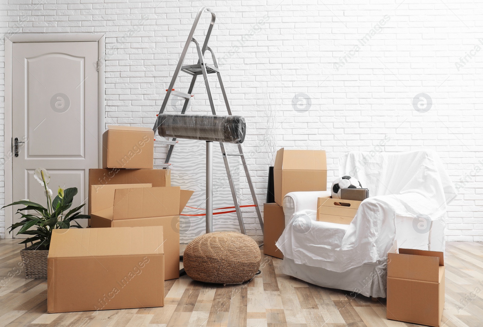 Photo of Cardboard boxes and household stuff in living room. Moving day