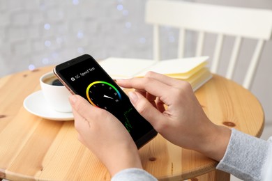 5G speed test. Woman using mobile phone at table, closeup