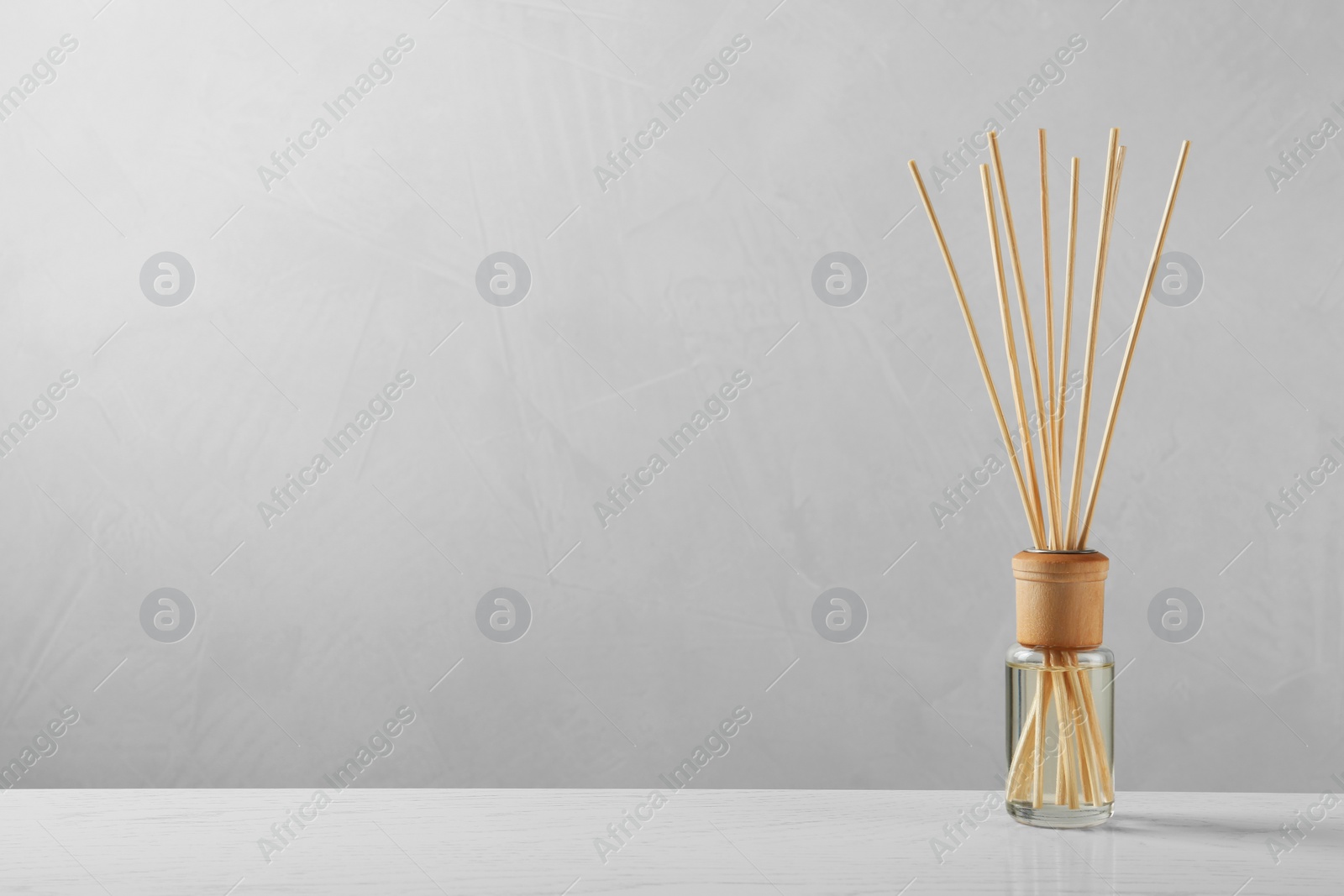 Photo of Reed air freshener on table against grey background, space for text