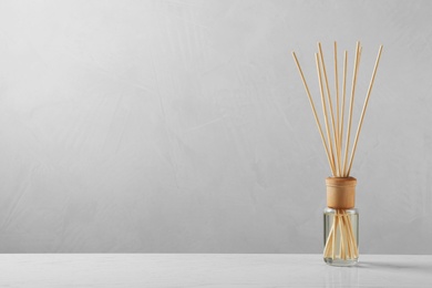 Photo of Reed air freshener on table against grey background, space for text