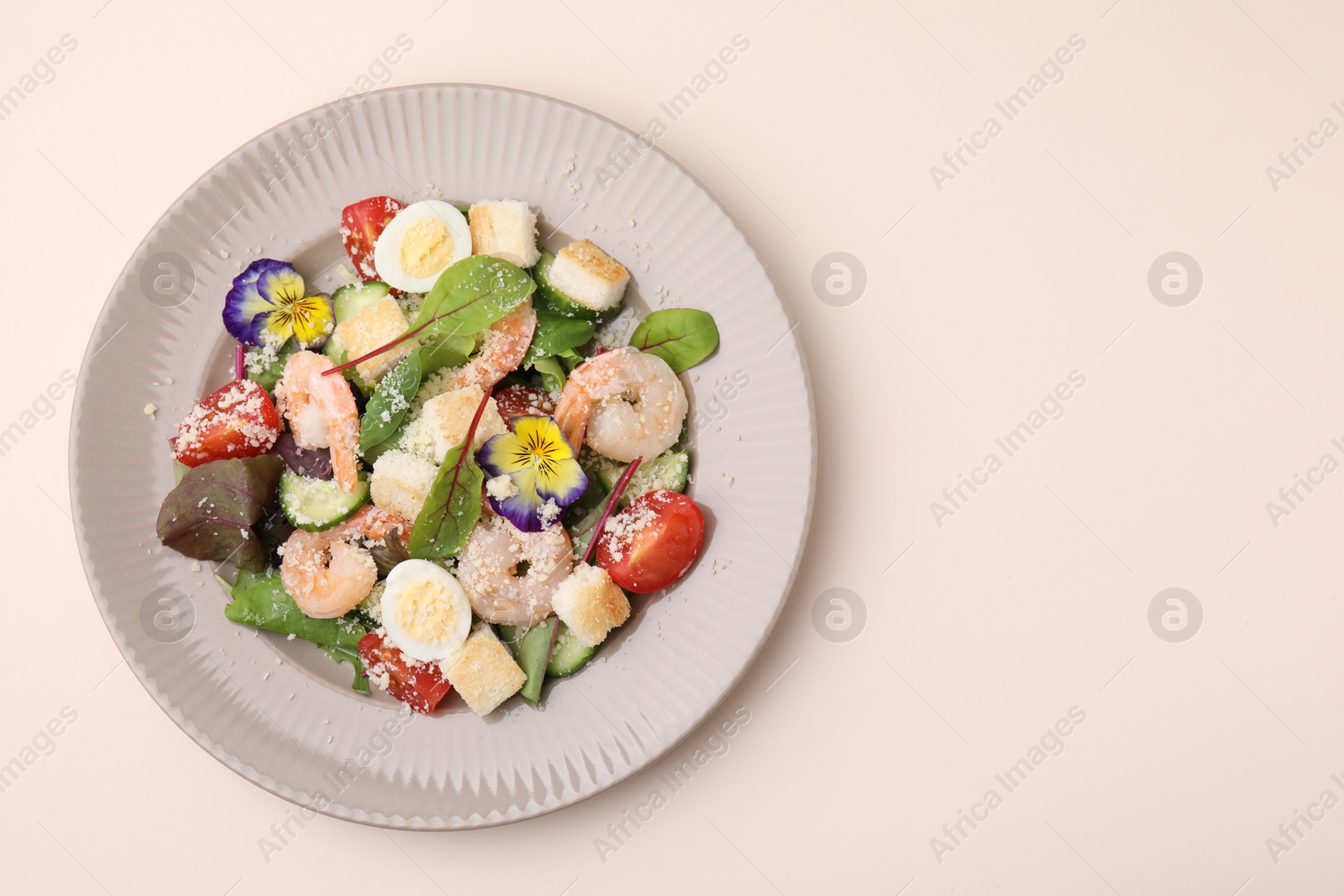 Photo of Delicious Caesar salad with shrimps on beige background, top view. Space for text