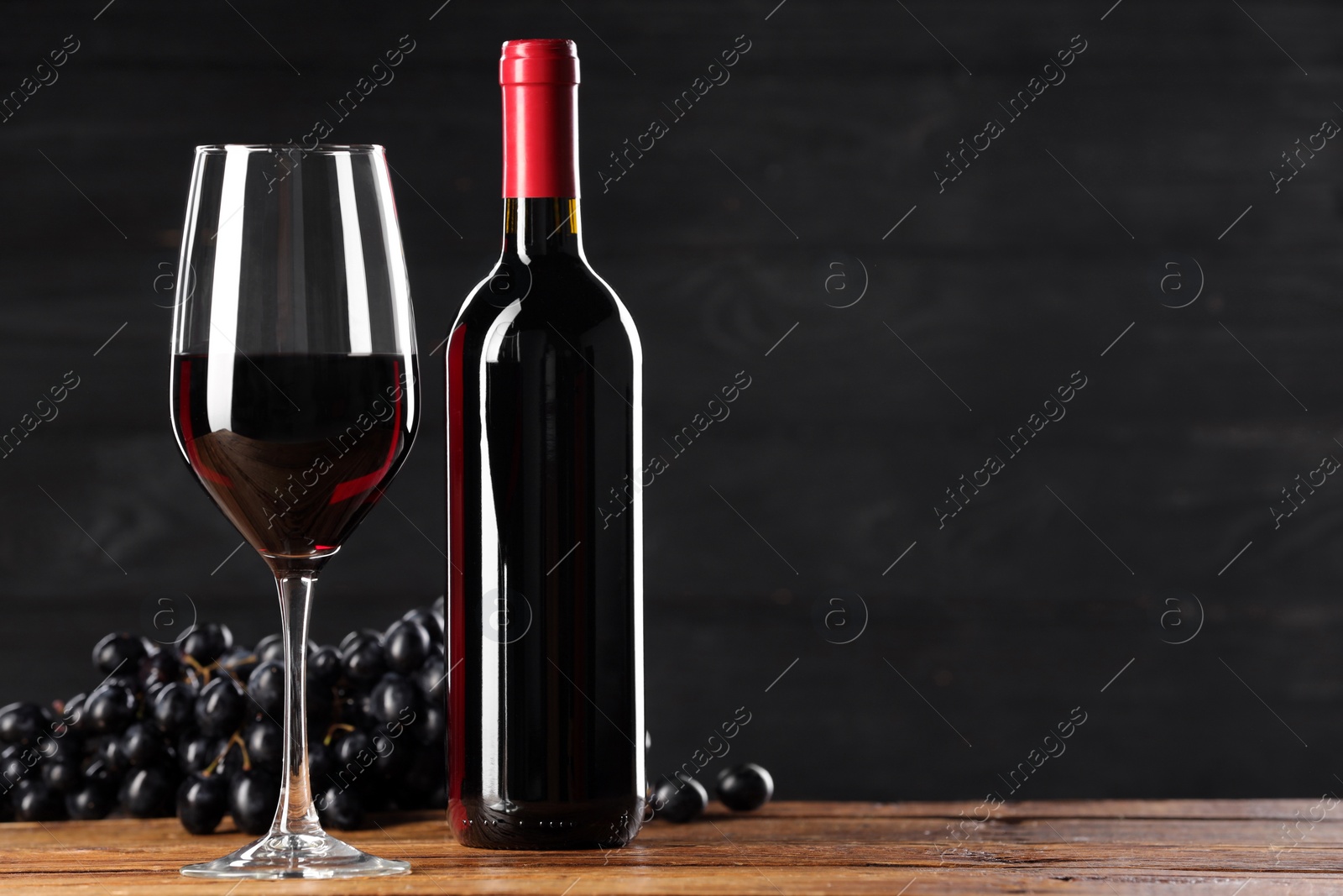 Photo of Delicious wine and ripe grapes on wooden table. Space for text