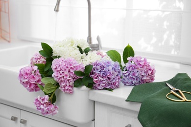 Photo of Bouquet with beautiful hydrangea flowers in sink