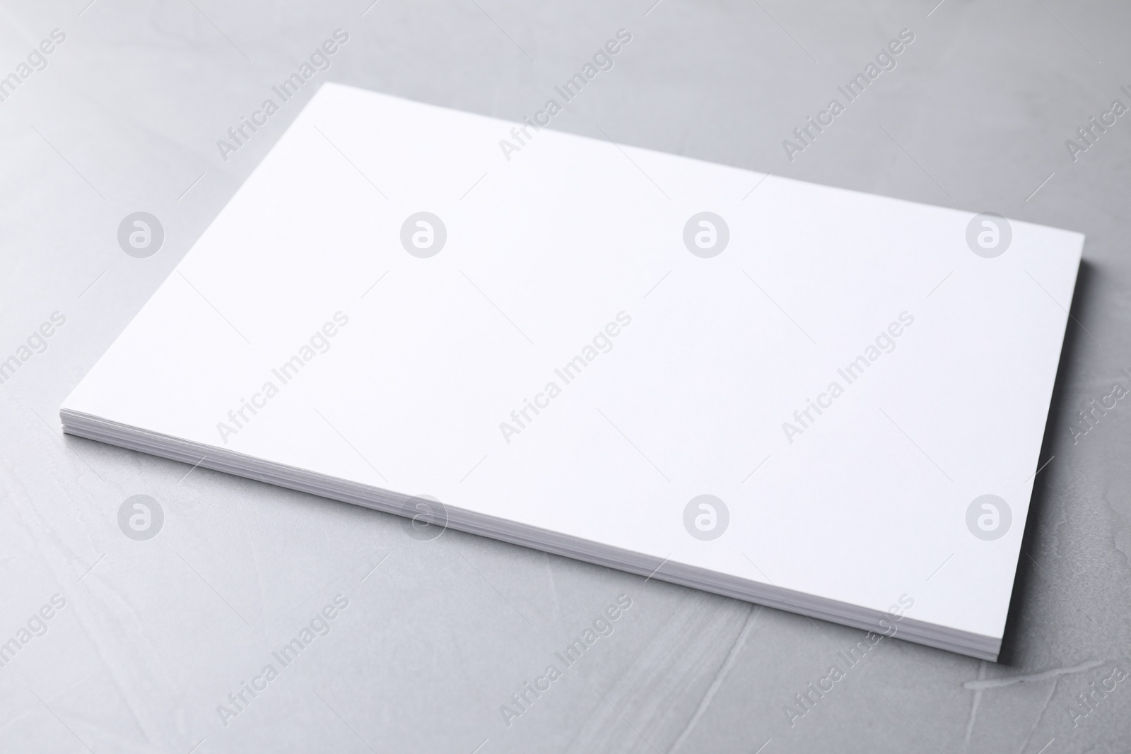 Photo of Blank paper sheets on light grey stone background. Mock up for design