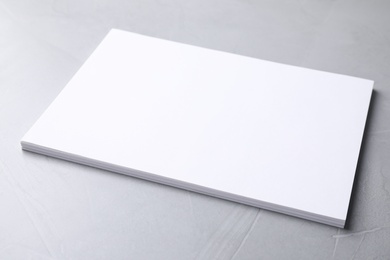 Blank paper sheets on light grey stone background. Mock up for design