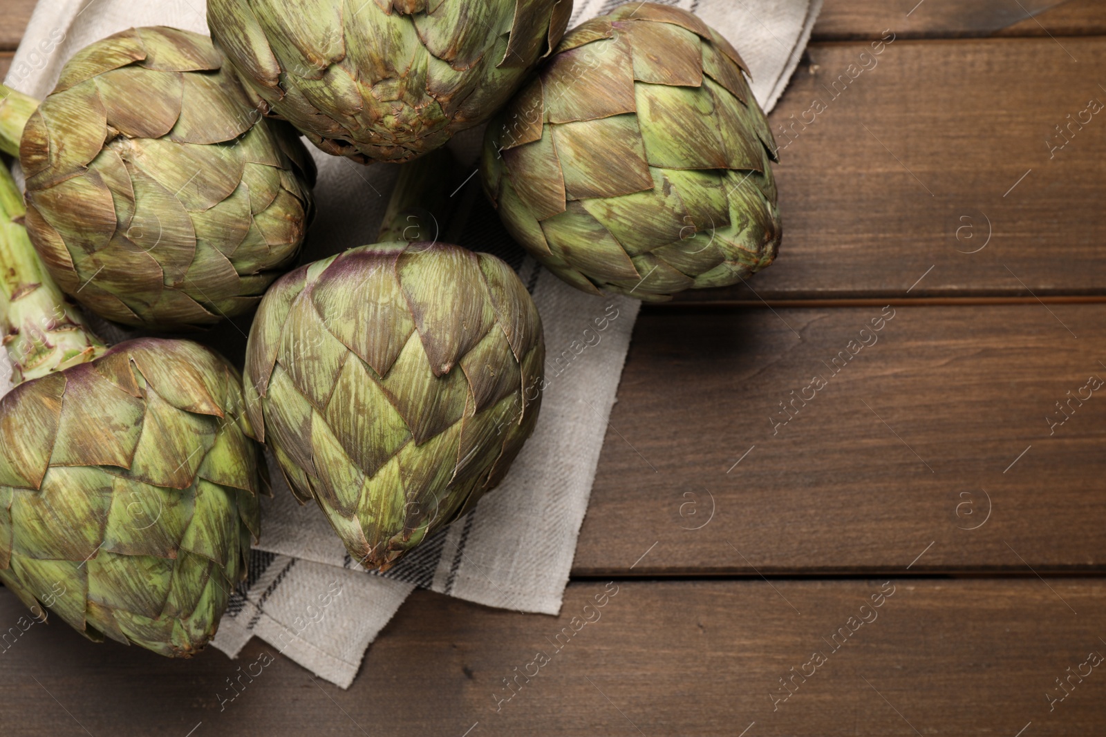 Photo of Fresh raw artichokes on wooden table, flat lay. Space for text