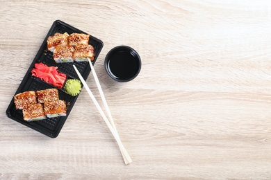 Photo of Tasty sushi rolls served on wooden table, top view with space for text. Food delivery