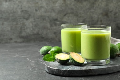 Photo of Fresh feijoa smoothie and fresh fruits on grey table, space for text