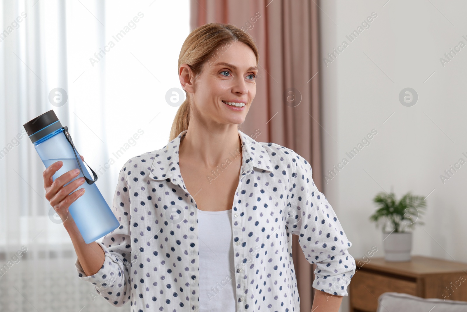 Photo of Woman with bottle of water in room