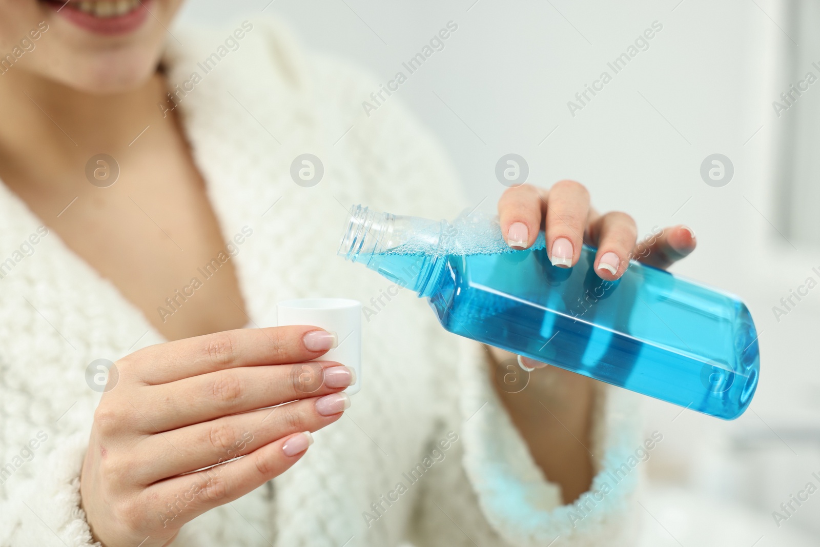 Photo of Young woman using mouthwash on light background, closeup