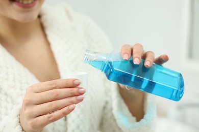 Photo of Young woman using mouthwash on light background, closeup