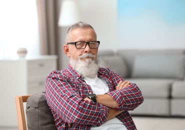 Photo of Portrait of handsome mature man with glasses sitting on chair in room