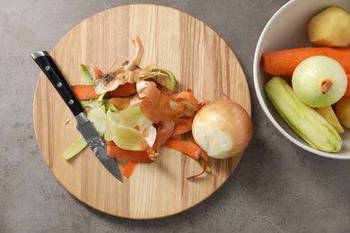 Photo of Peels of fresh vegetables and knife on grey table, flat lay