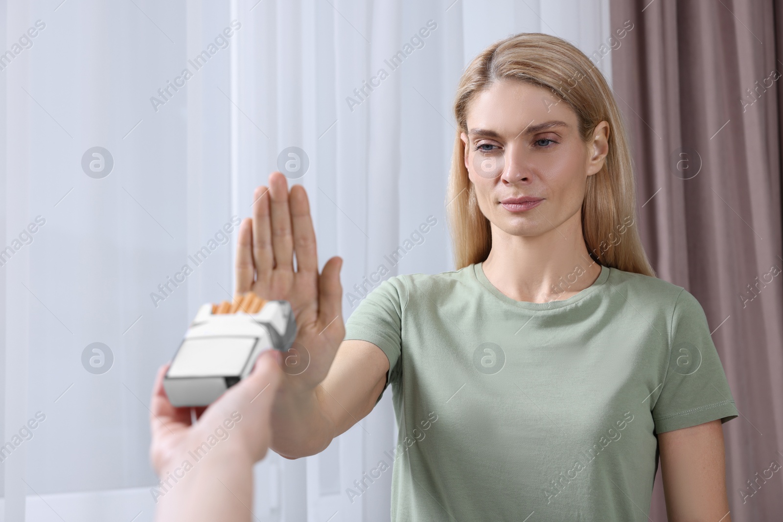 Photo of Woman refusing cigarettes on light background. Quitting smoking concept