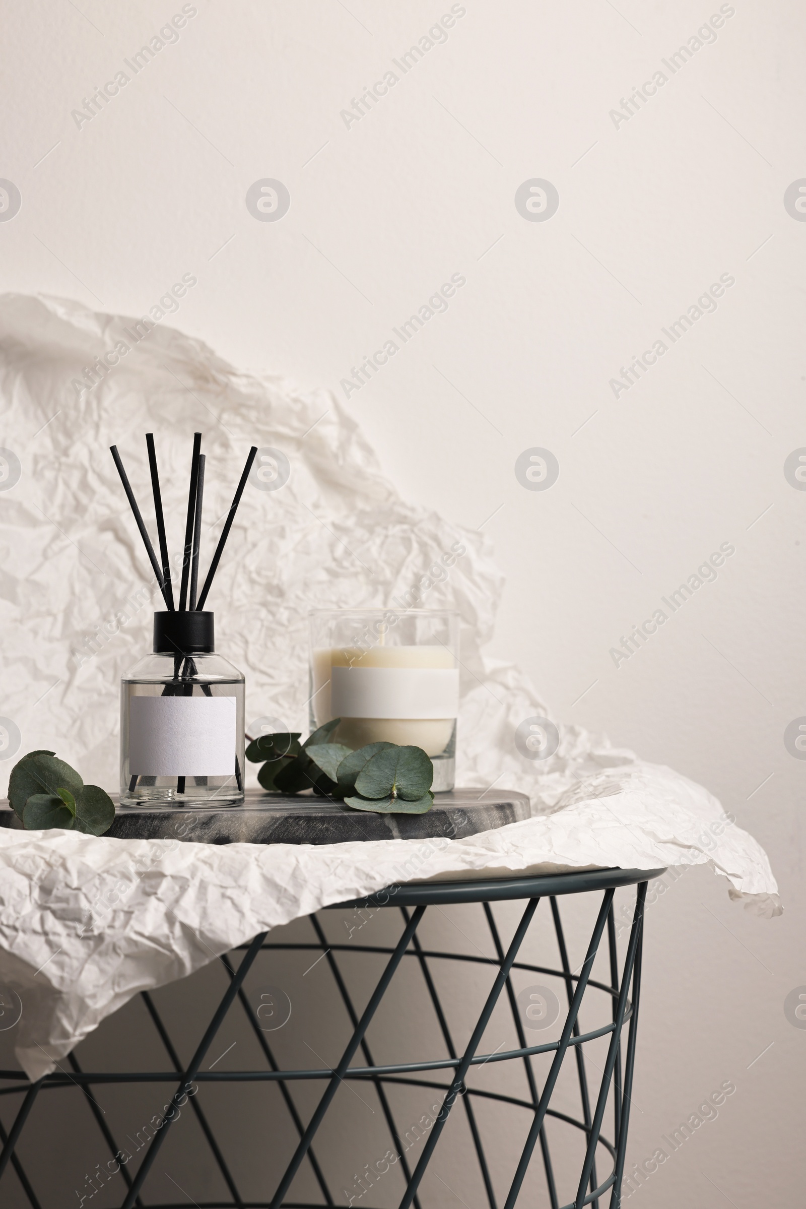Photo of Aromatic reed air freshener, eucalyptus leaves and candle on table, space for text