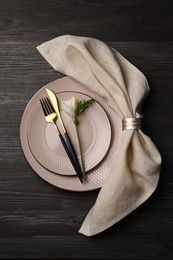 Stylish table setting. Plates, cutlery, napkin and floral decor on dark wooden background, top view