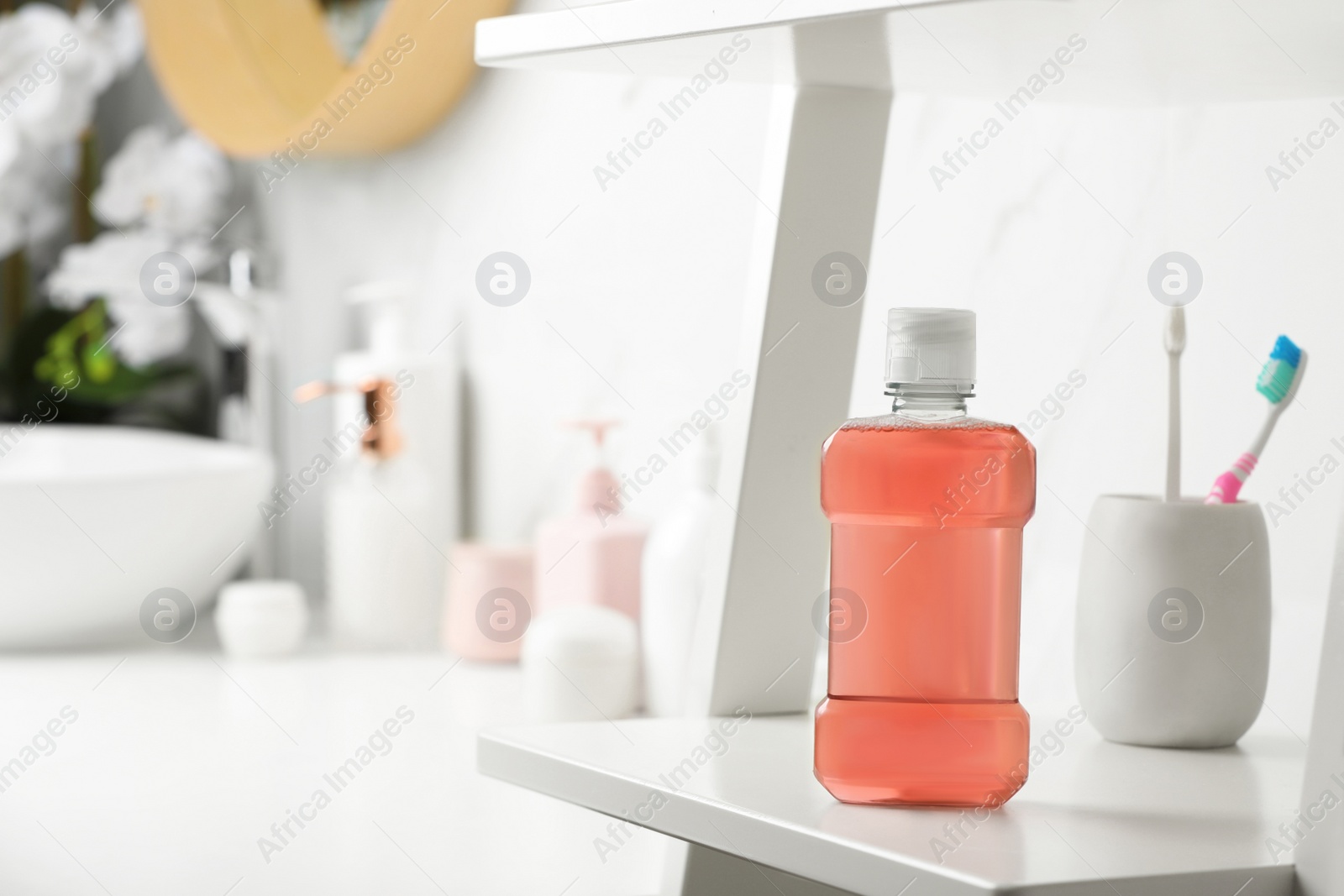 Photo of Bottle of mouthwash on white shelf in bathroom, space for text