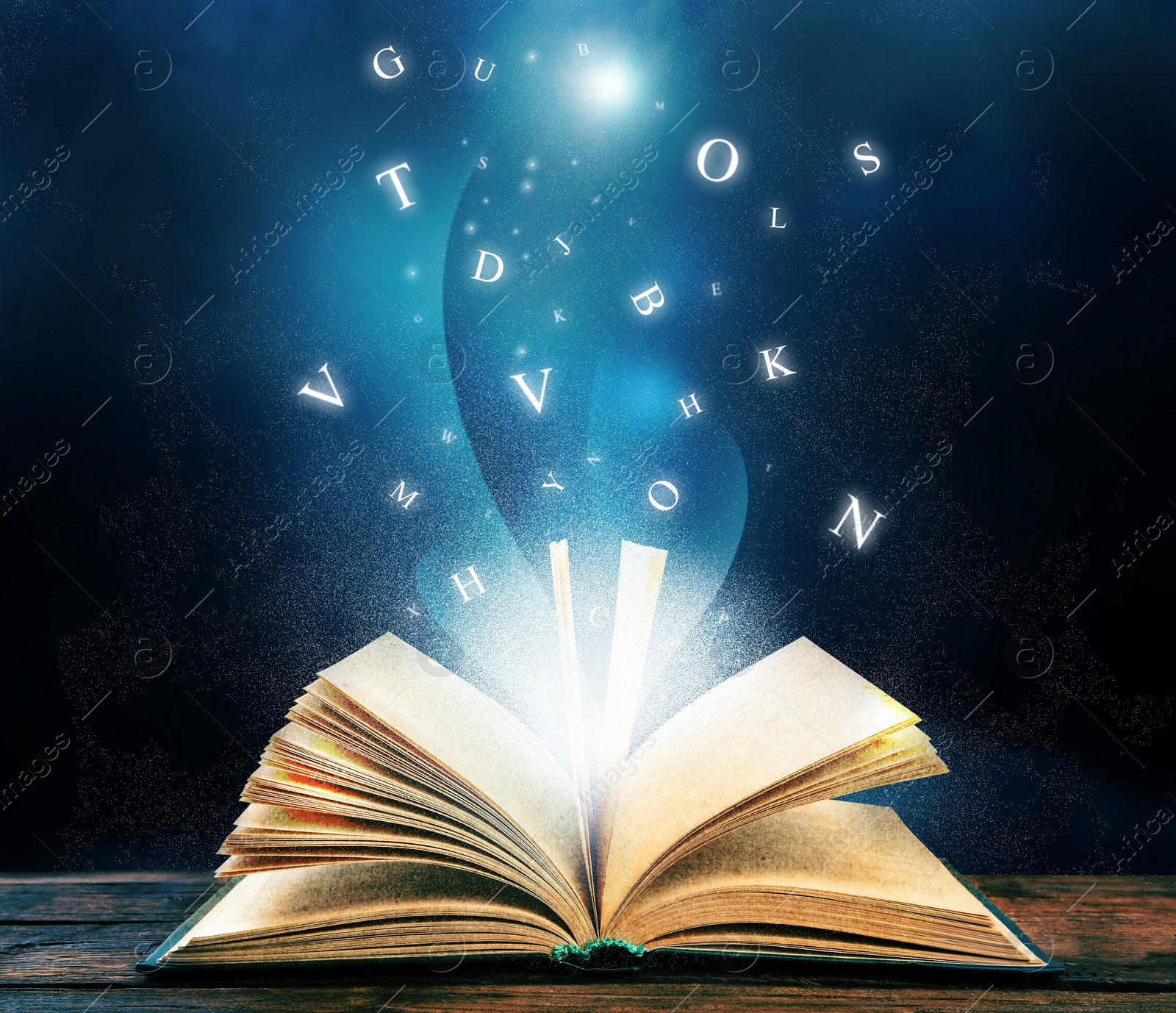 Image of Open book with magic light and glowing letters flying out of it on wooden table against black background