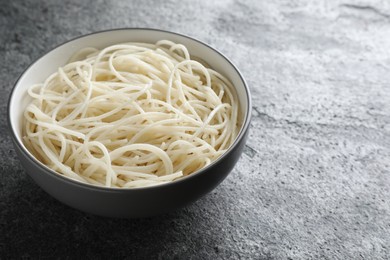 Bowl of tasty cooked rice noodles on grey table. Space for text